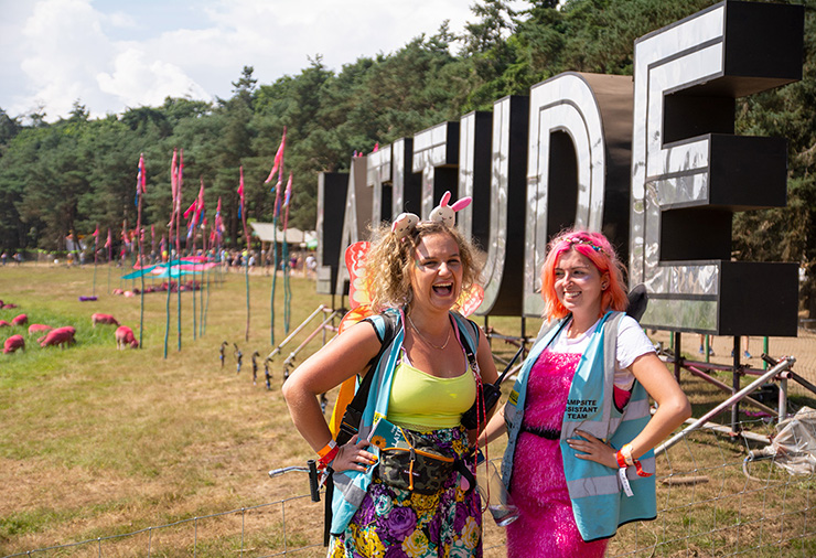 Festival Jobs and Work - Hotbox Events - Pixie marshals laughing in front of latitude sign 2022-001 740x506Px72Dpi